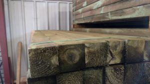 A tidy pile of square green treated posts in a lumber yard